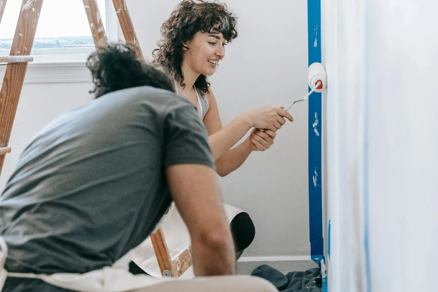 A man and woman painting the wall of their home.